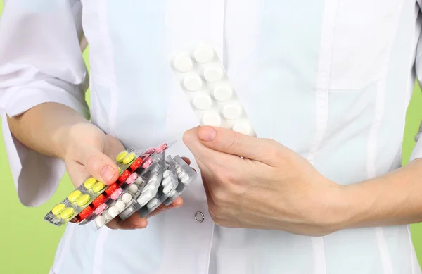 Close-up of female doctor hand holding pills, on color background — Stock Photo, Image
