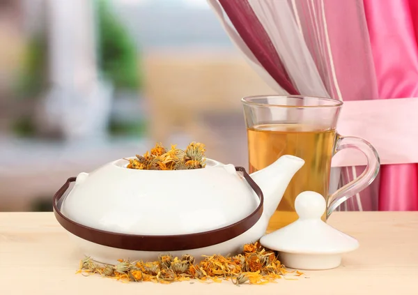 Dried herbs in teapot on wooden table, on bright background. Conceptual photo of herbal tea. — Stock Photo, Image