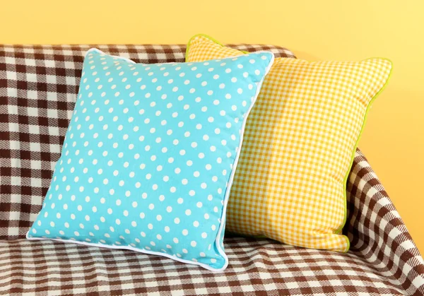 Färgglada kuddar på soffan på gul bakgrund — Stockfoto
