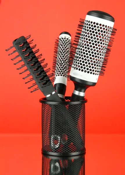 Iron basket with round hair brushes, on color background — Stock Photo, Image