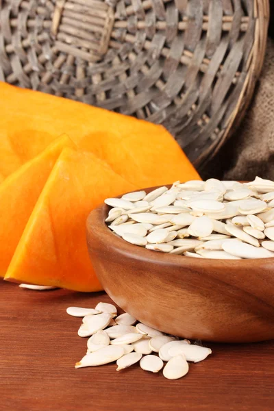Pumpkin seeds in wooden bowl, on sackcloth background — Stock Photo, Image