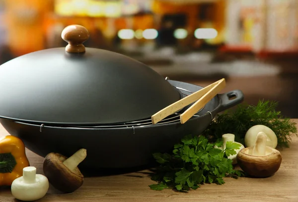 Padella wok nero e verdure sul tavolo di legno della cucina, primo piano — Foto Stock