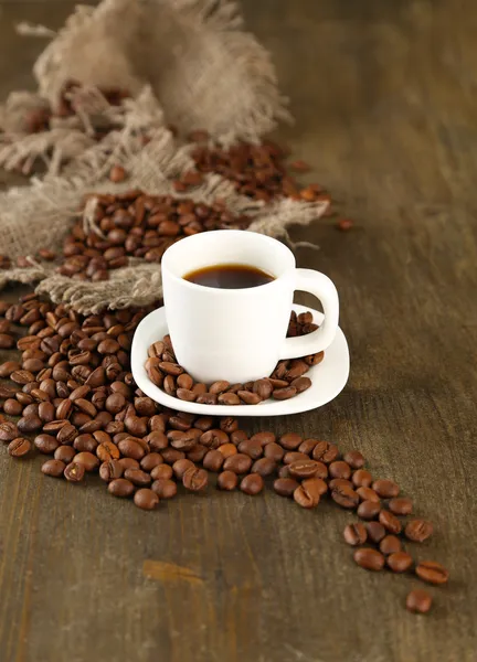 Xícara de café e grãos de café em fundo de madeira — Fotografia de Stock