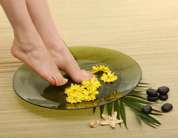 Frauenfüße in Wellnessschale mit Wasser, auf Bambusmatte — Stockfoto