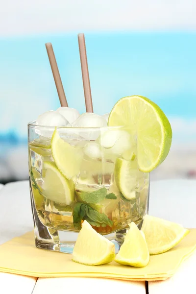 Cocktailglas mit Limette und Minze auf weißem Holztisch auf hellem Hintergrund — Stockfoto