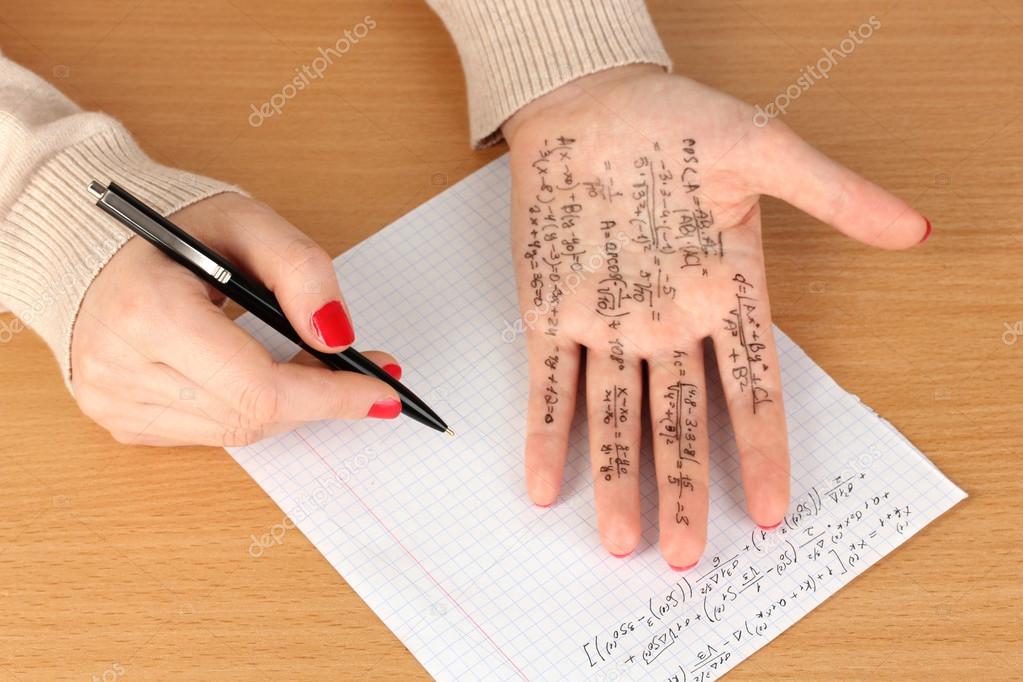 Write cheat sheet on hand on wooden table close-up