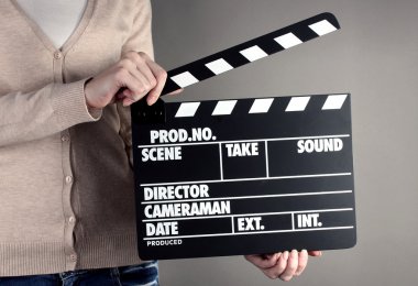 Film üretim clapper panosundaki gri arka plan üzerinde eller