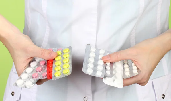 Крупним планом жінка-лікар рука тримає таблетки, на кольоровому фоні — стокове фото