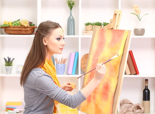 Όμορφη νεαρή γυναίκα ζωγράφος στην εργασία, σε δωμάτιο εσωτερικό φόντο — Φωτογραφία Αρχείου