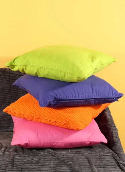 Almohadas de colores en el sofá sobre fondo amarillo — Foto de Stock