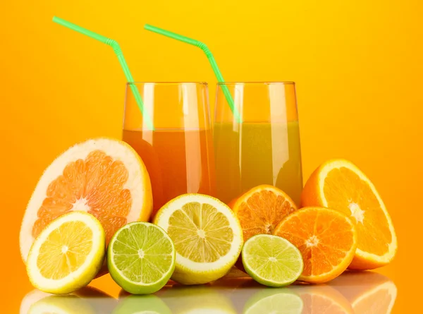 Wiele dojrzałych owoców cytrusowych z soków na pomarańczowym tle — Zdjęcie stockowe