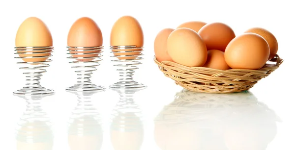 Viele Eier im Korb und im Eierbecher isoliert auf weiß — Stockfoto
