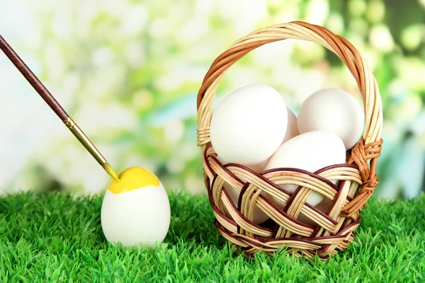 Huevos de Pascua en cesta sobre hierba sobre fondo brillante —  Fotos de Stock