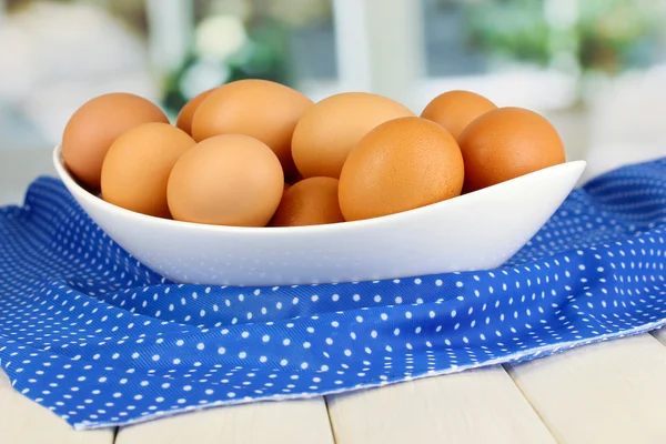 Ovos em tigela branca na mesa de madeira no fundo da janela — Fotografia de Stock