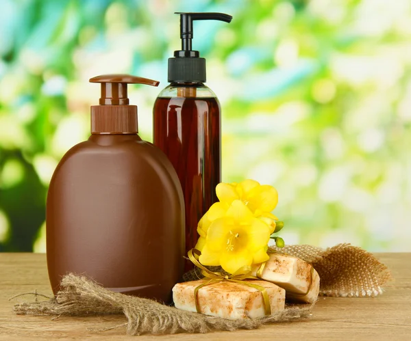 Vloeibare en handgemaakte zeep op houten tafel, op groene achtergrond — Stockfoto