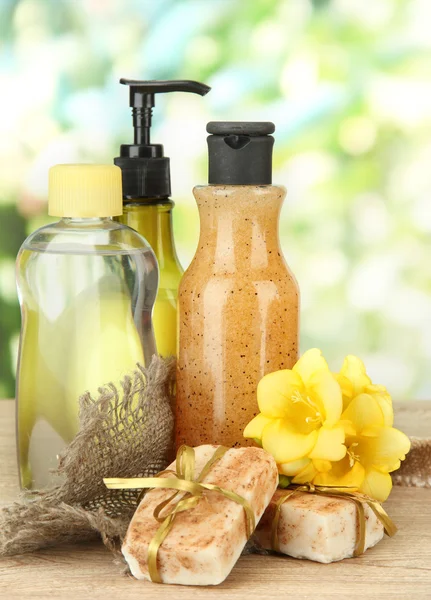 Liquid and hand-made soaps on wooden table, on green background — Stock Photo, Image