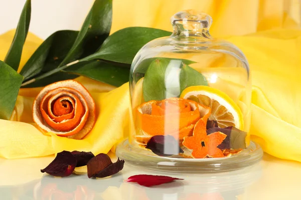Decorative rose from dry orange peel in glass vase on yellow fabric background — Stock Photo, Image