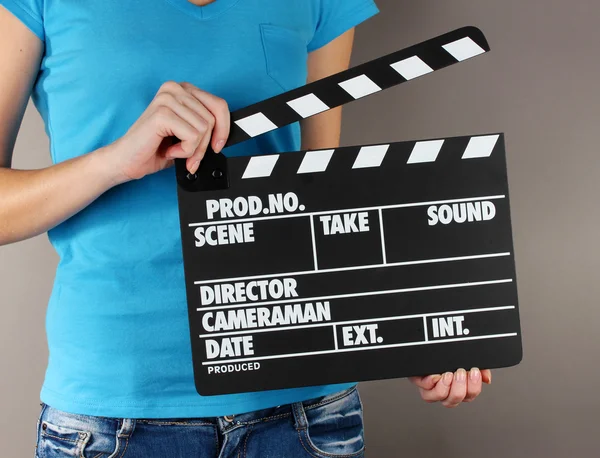 Film üretim clapper panosundaki gri arka plan üzerinde eller