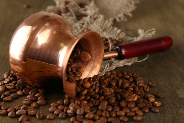 Coffee pot with coffee beans on wooden background — Stock Photo, Image