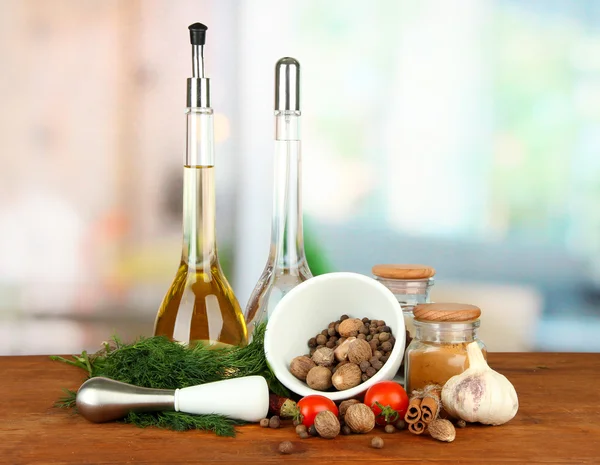 Composition of mortar, bottles with olive oil and vinegar, and green herbals, on bright background — Stock Photo, Image