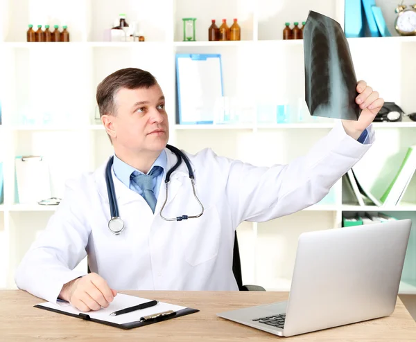 Medical doctor analysing x-ray image at desk — Stock Photo, Image