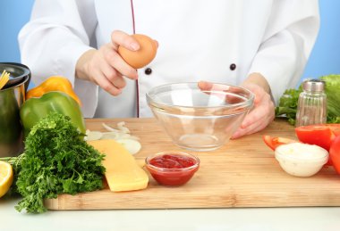 dişi ara mavi zemin üzerine cam kaseye yumurta eller.