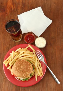 patates kızartması ve ahşap zemin üzerinde soğuk içecek ile lezzetli peynirli burger