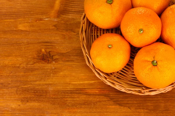 Smakelijke mandarijnen op rieten mat op houten achtergrond — Stockfoto