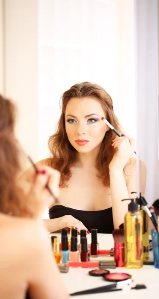 Молодая красивая женщина делает макияж возле зеркала — стоковое фото