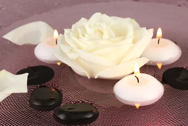 Pierres de spa avec fleur et bougies dans l'eau sur plaque — Photo