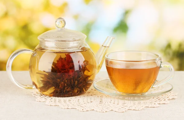 Té verde exótico con flores en tetera de vidrio sobre fondo brillante — Foto de Stock