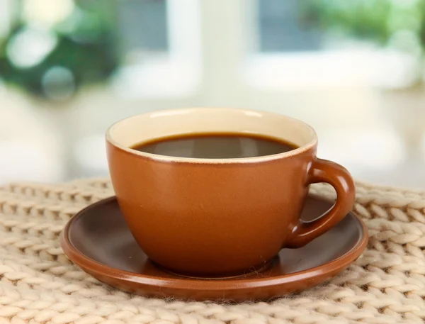 Cup of coffee with scarf on table in room — Stock Photo, Image