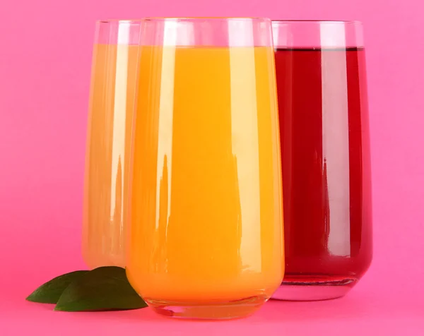 Glasses of juise and leafs on pink background — Stock Photo, Image