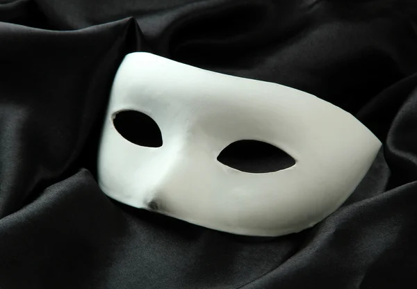 Máscara branca, em tecido de seda preta — Fotografia de Stock