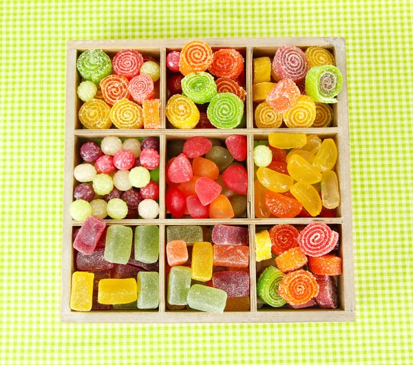 Caramelle multicolore in scatola di legno, su sfondo colore — Foto Stock