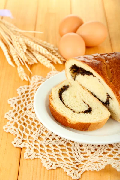 Pane con semi di papavero su piatto di colore, su sfondo di legno — Foto Stock