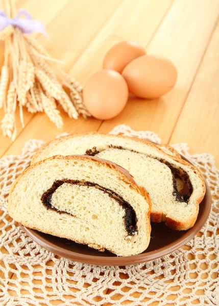 Loaf with poppy seeds on color plate, on wooden background — Stock Photo, Image