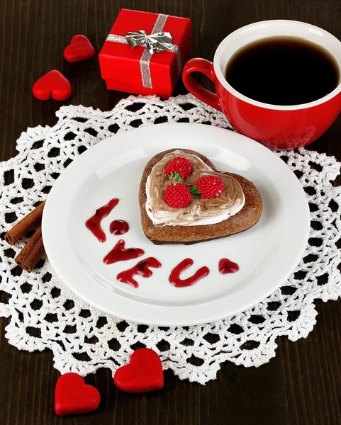Chocolate cookie in form of heart with cup of coffee on wooden table close-up — Stock Photo, Image