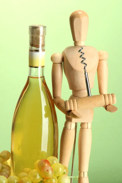 Manequim com saca-rolhas e garrafa de vinho, sobre fundo verde — Fotografia de Stock