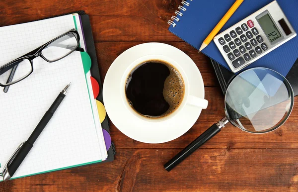 Tasse de café sur la table de travail recouverte de documents close up — Photo