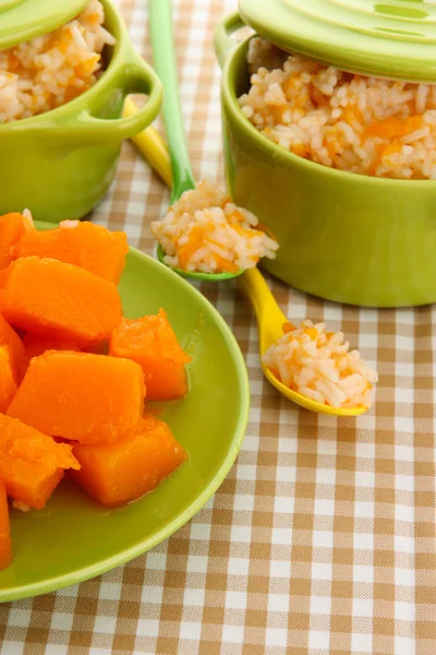 Taste rice porridge with pumpkin in saucepans on tablecloth background Royalty Free Stock Images