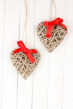 ahşap arka plan üzerinde kırmızı fiyonklu hasır Kalpler