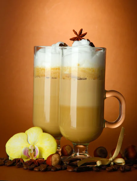 Fragrant coffee latte in glasses cups with spices, on brown background — Stock Photo, Image