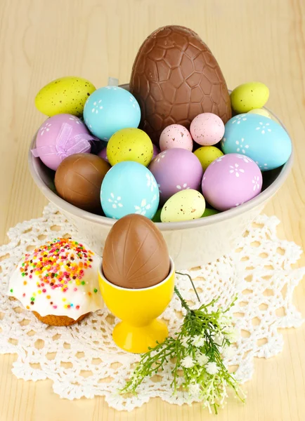Skład jajka wielkanocne i czekolady i Simmel w drewniany stół szczegół — Zdjęcie stockowe