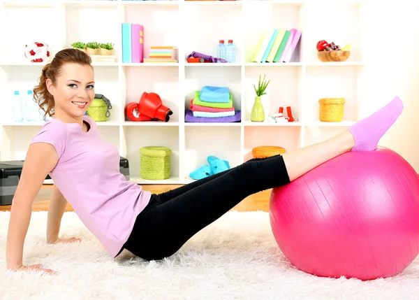 Mujer joven haciendo ejercicios de fitness con pelota de gimnasio en casa — Foto de Stock