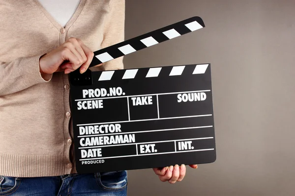 电影生产拍板板在双手上灰色背景 — 图库照片