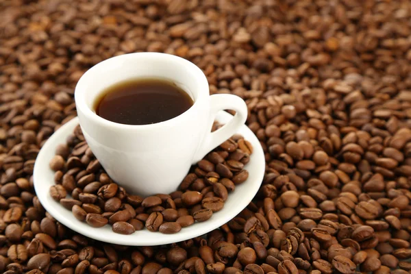 Xícara de café em grãos de café fundo — Fotografia de Stock