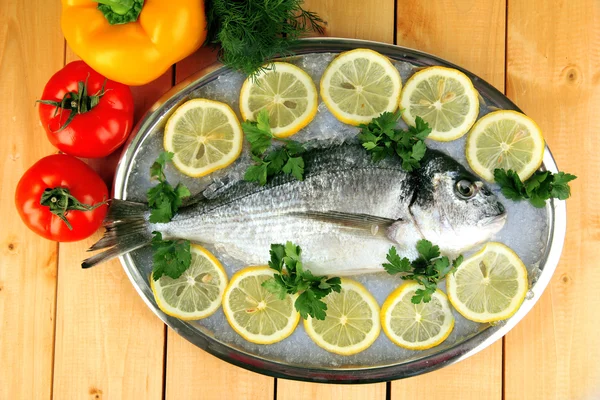 Fresh fish of dorado on tray with lemon and parsley on wooden table — Stock Photo, Image