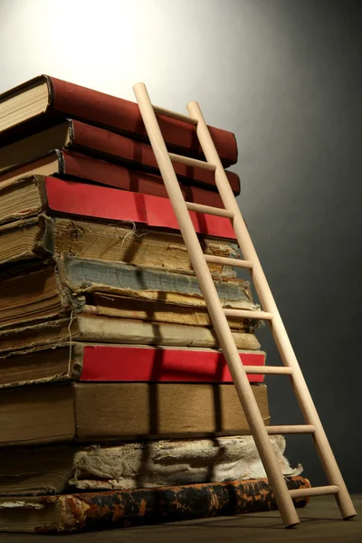 Old books and wooden ladder, on grey background