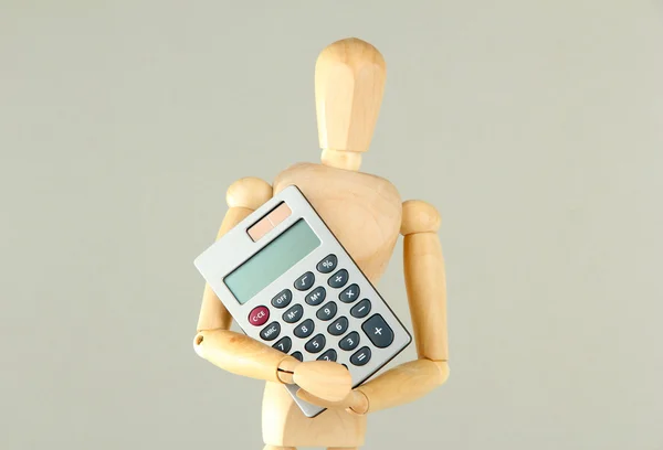 Wooden mannequin with calculator on grey background — Stock Photo, Image